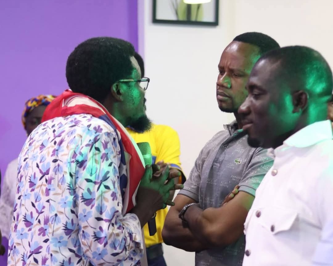 a picture of Dr Essel speaking to two men during a church service