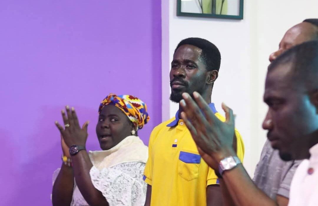 a picture of the church congregation, in the picture is a woman, a man in wyelllow and two men